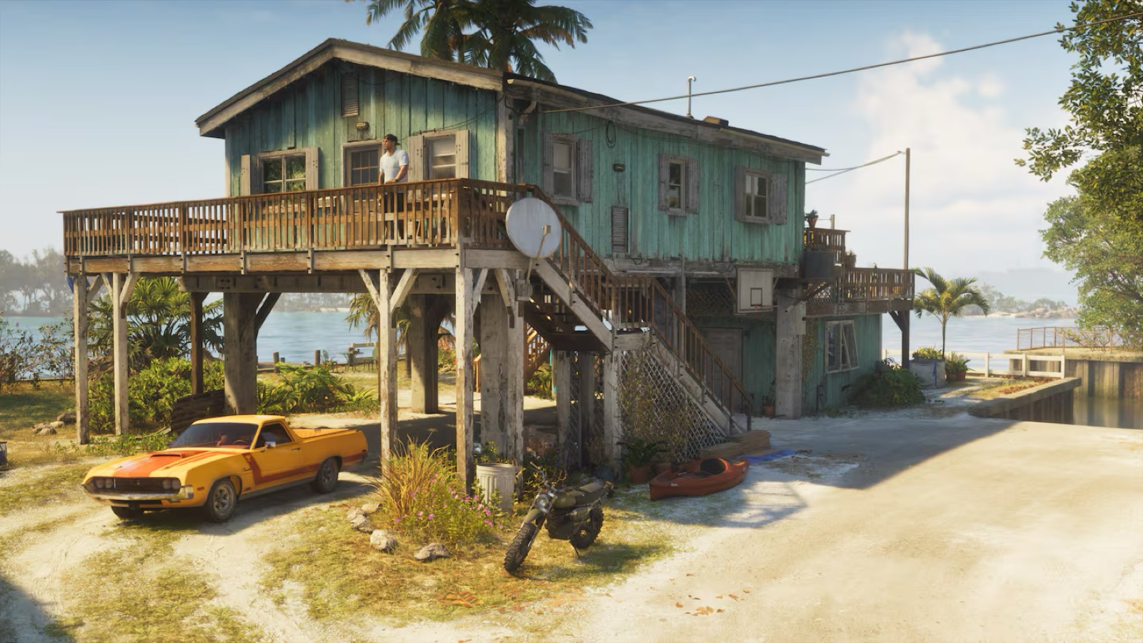 A stilt house with vehicles parked underneath, including a dirt bike and a kayak